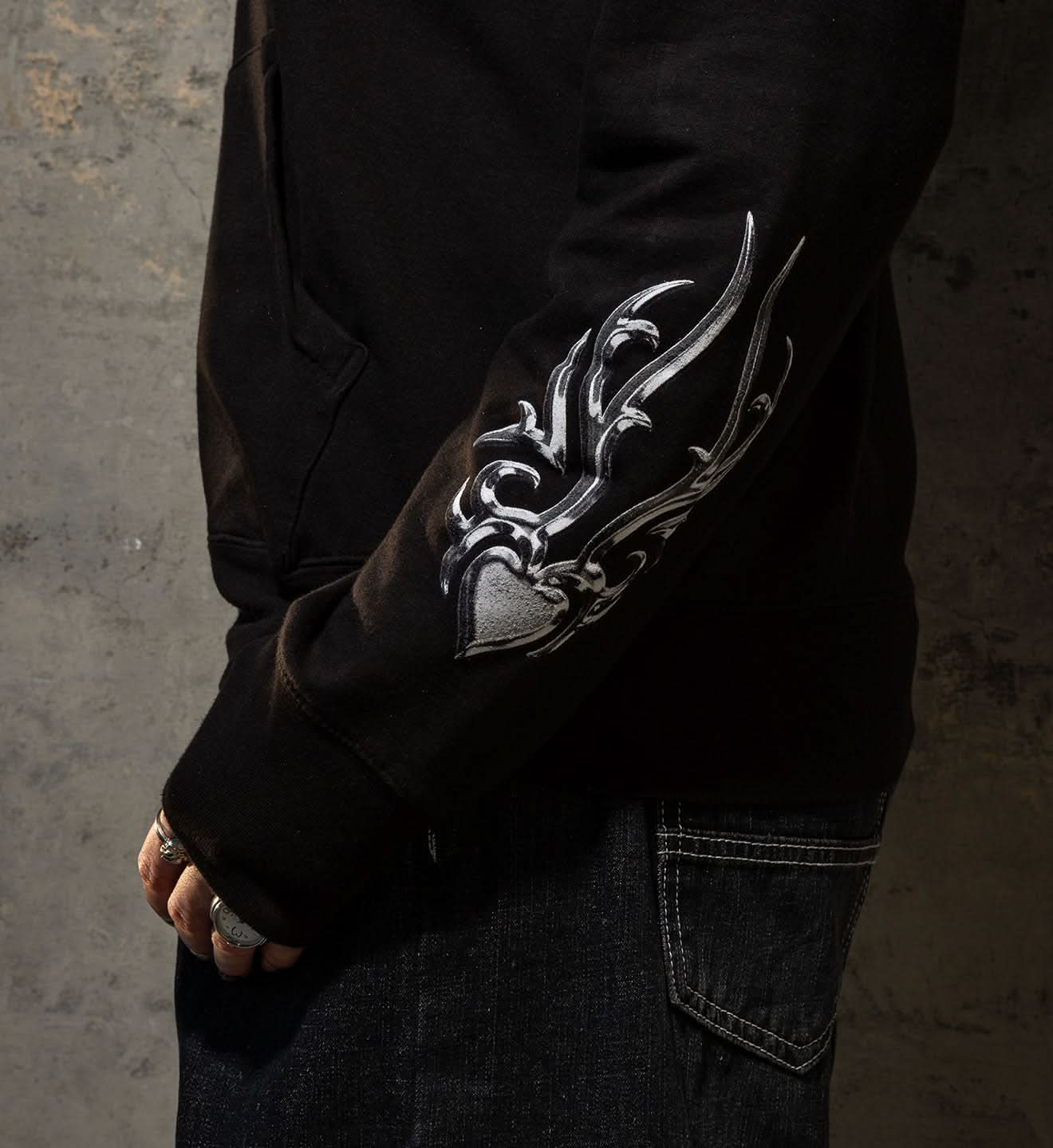 Black long-sleeve shirt with silver tribal design on a textured gray background