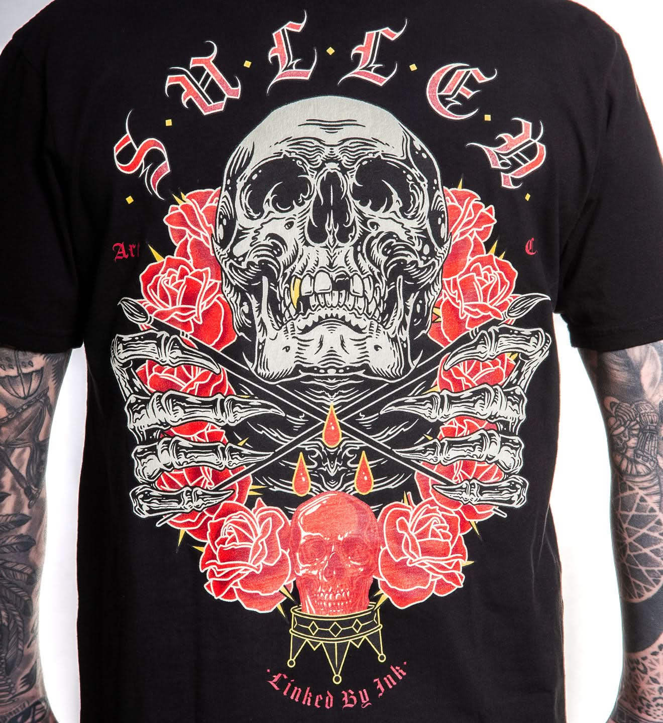 Black t-shirt with a skull and roses design on a plain background