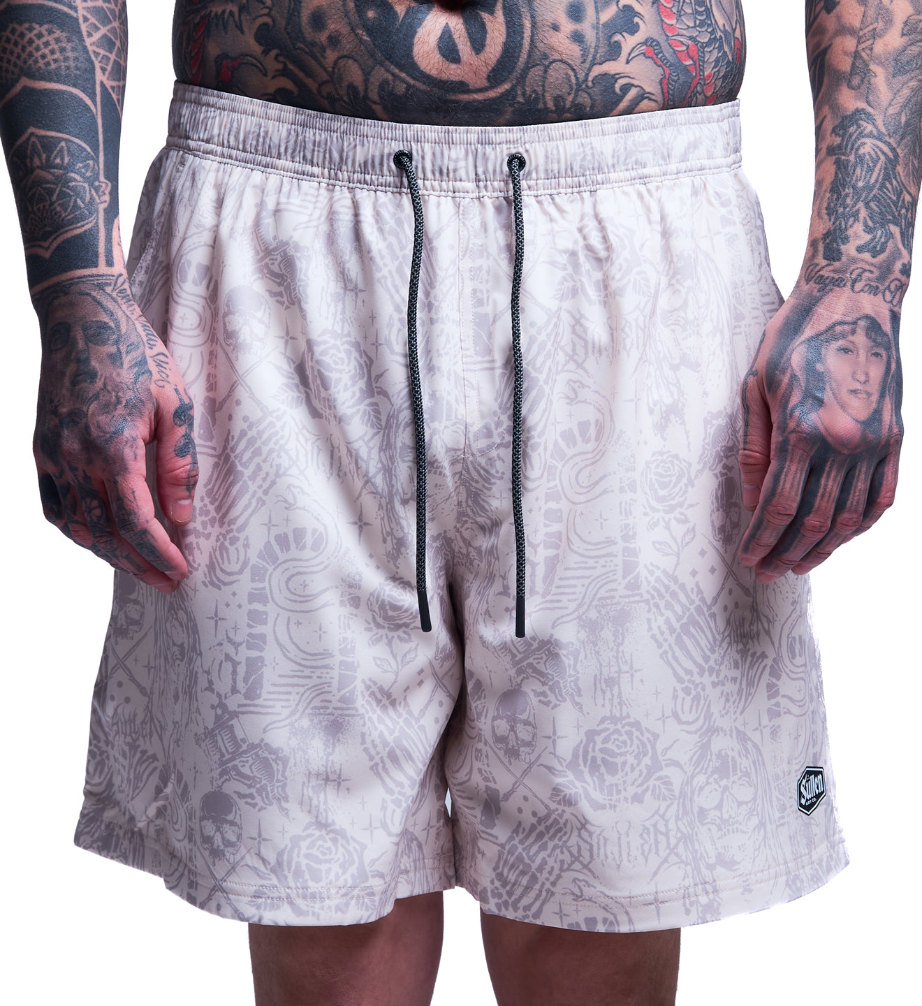 White patterned shorts worn by a person with tattoos on a white background