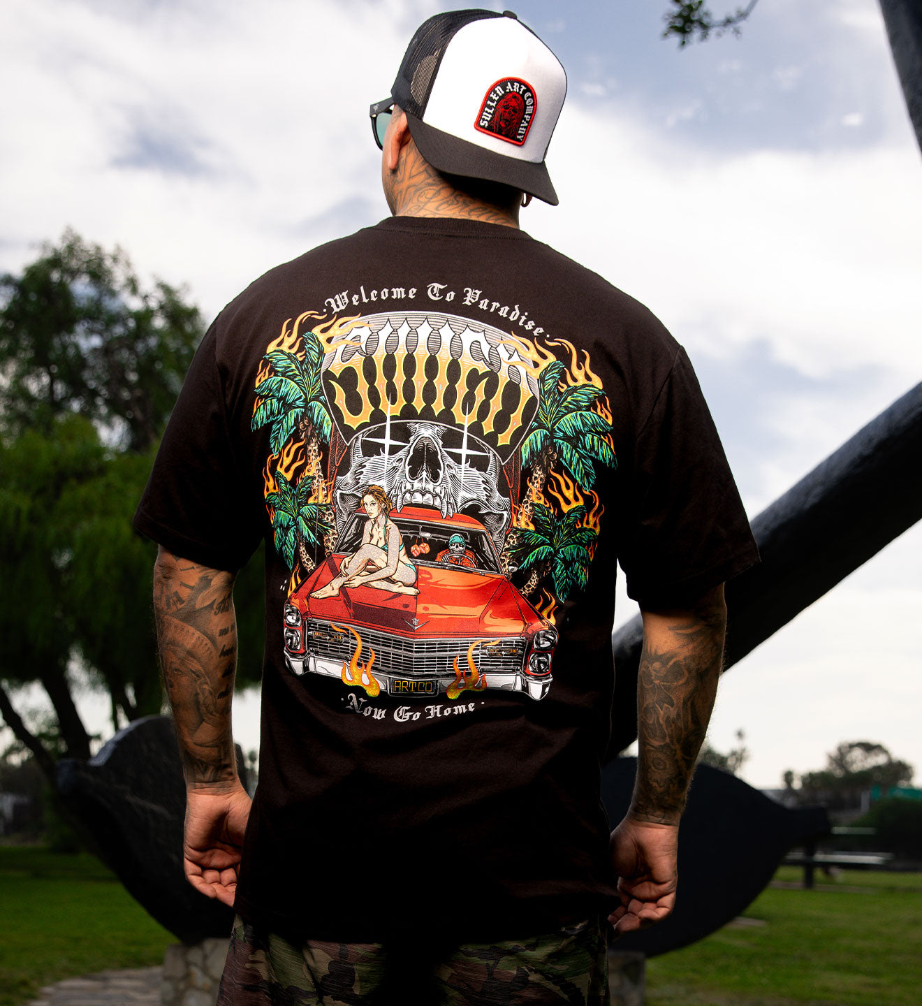 Person wearing a black t-shirt with a colorful graphic design outdoors.