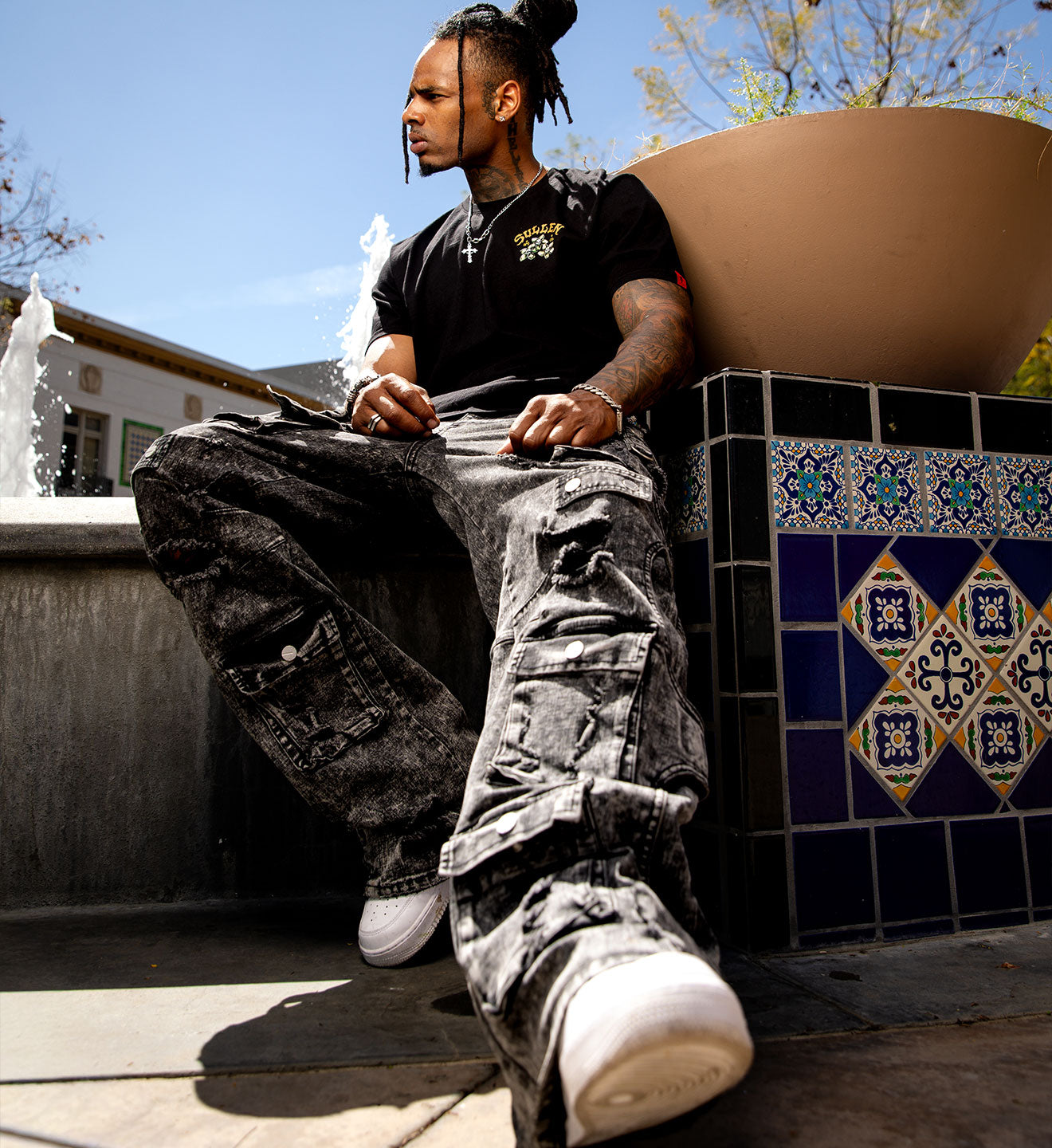 Person sitting on a ledge with decorative tiles and a fountain in the background