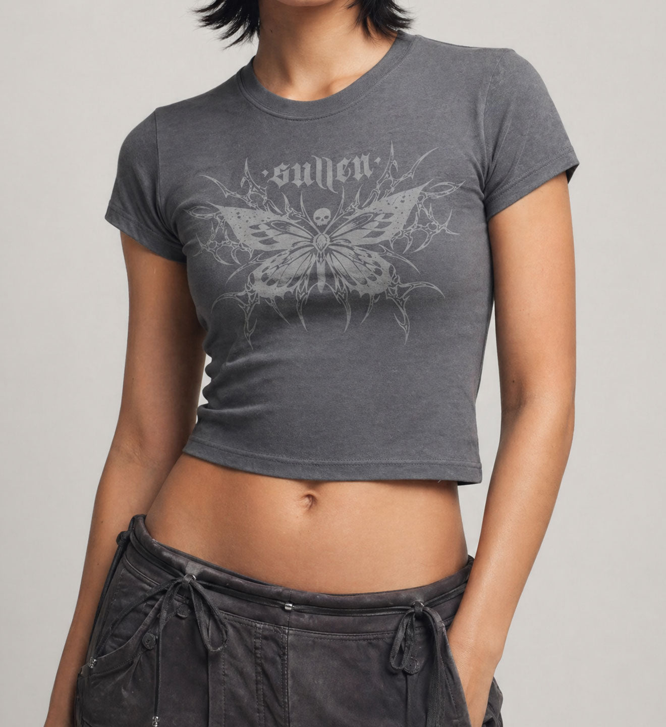 Person wearing a gray t-shirt with a butterfly design and 'sullen' text on a plain background