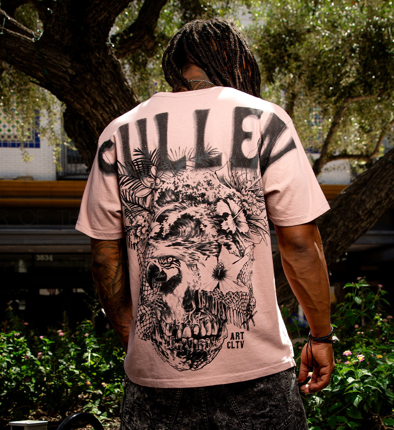 Person wearing a pink t-shirt with a graphic design and 'Gullen' branding outdoors.