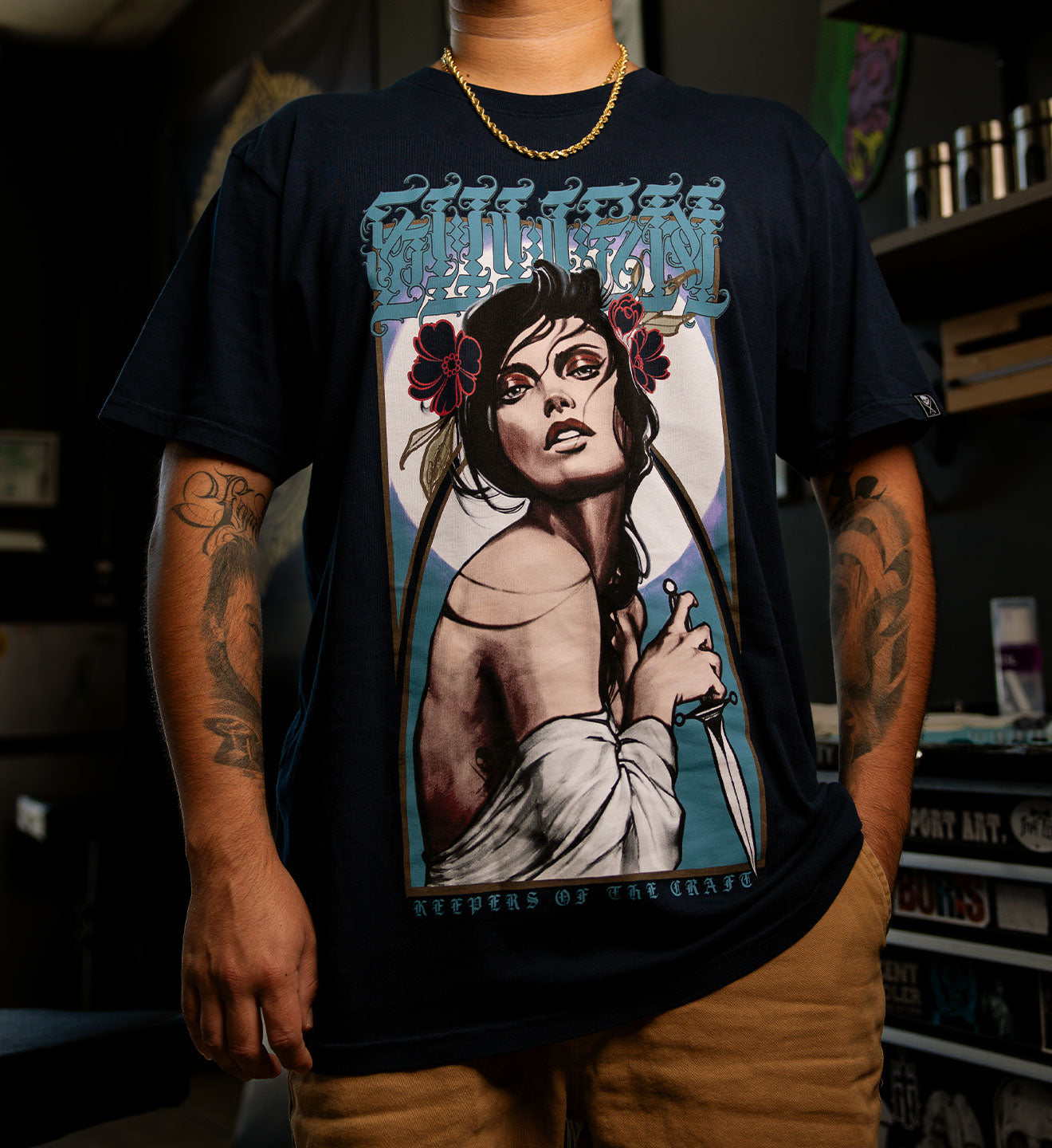 Person wearing a black t-shirt with a graphic design of a woman holding a gun and text.