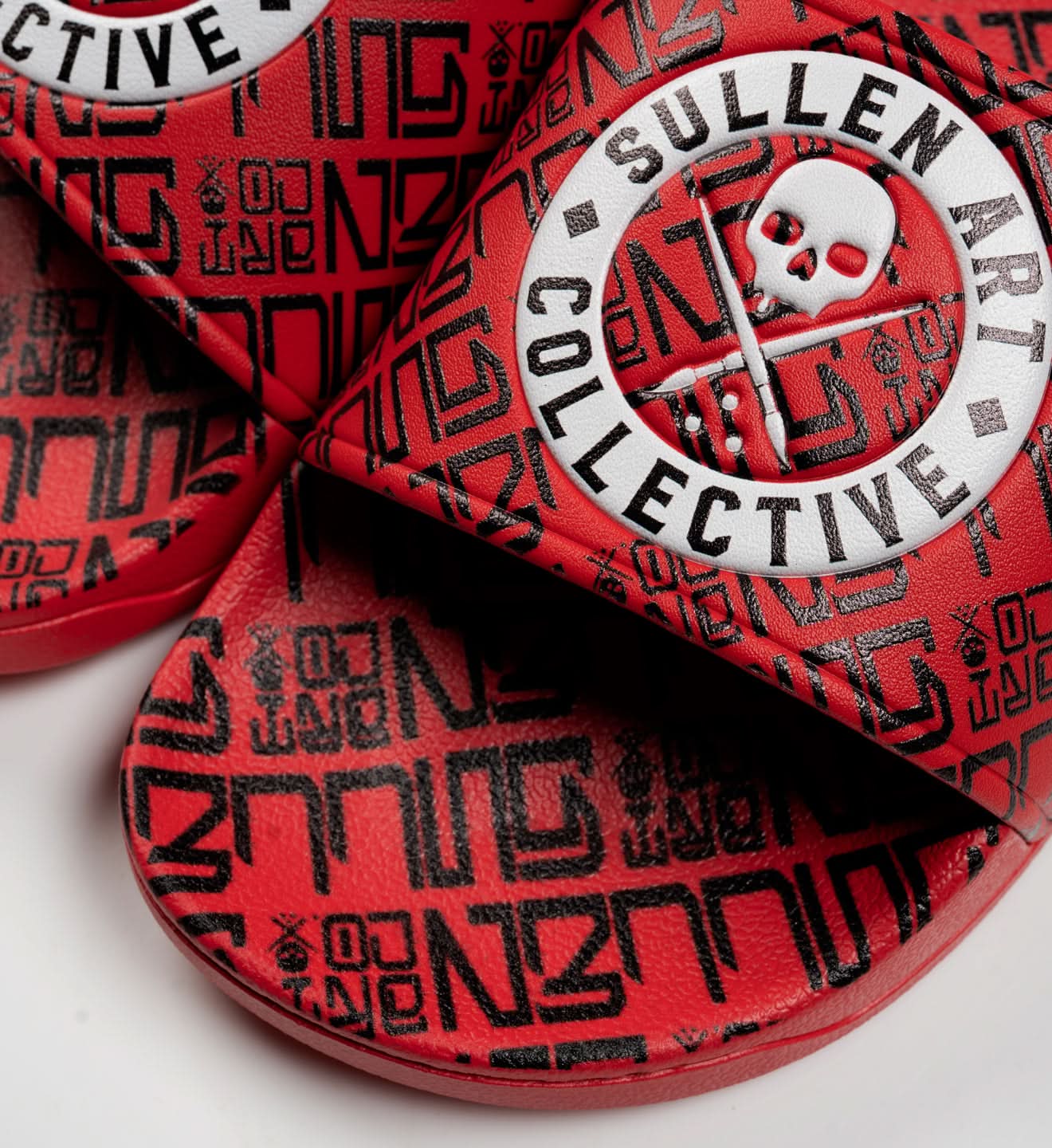 Red and black flip-flops with 'Sullen Art Collective' branding on a white background