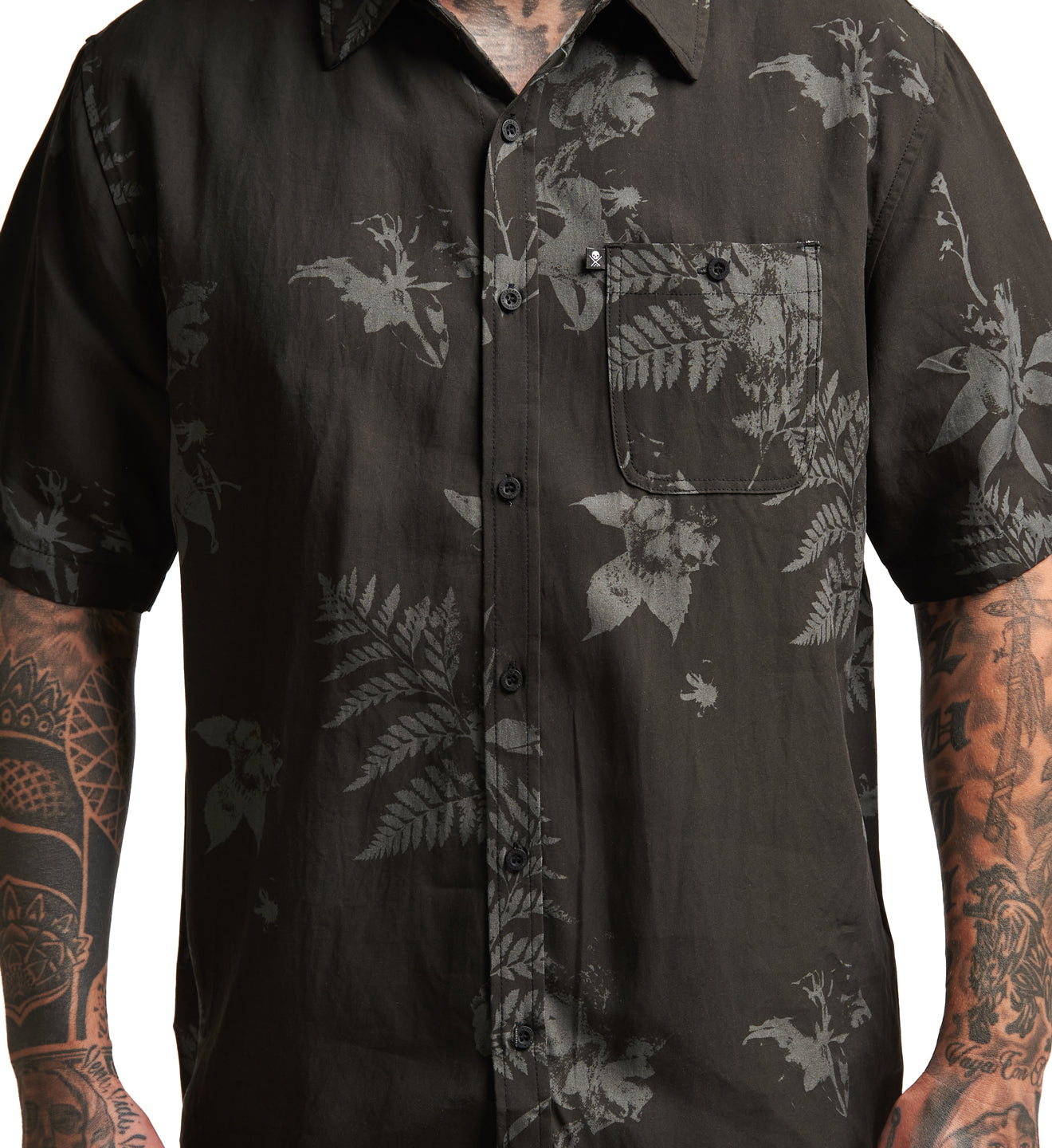 Black floral patterned shirt worn by a person with tattoos on a white background