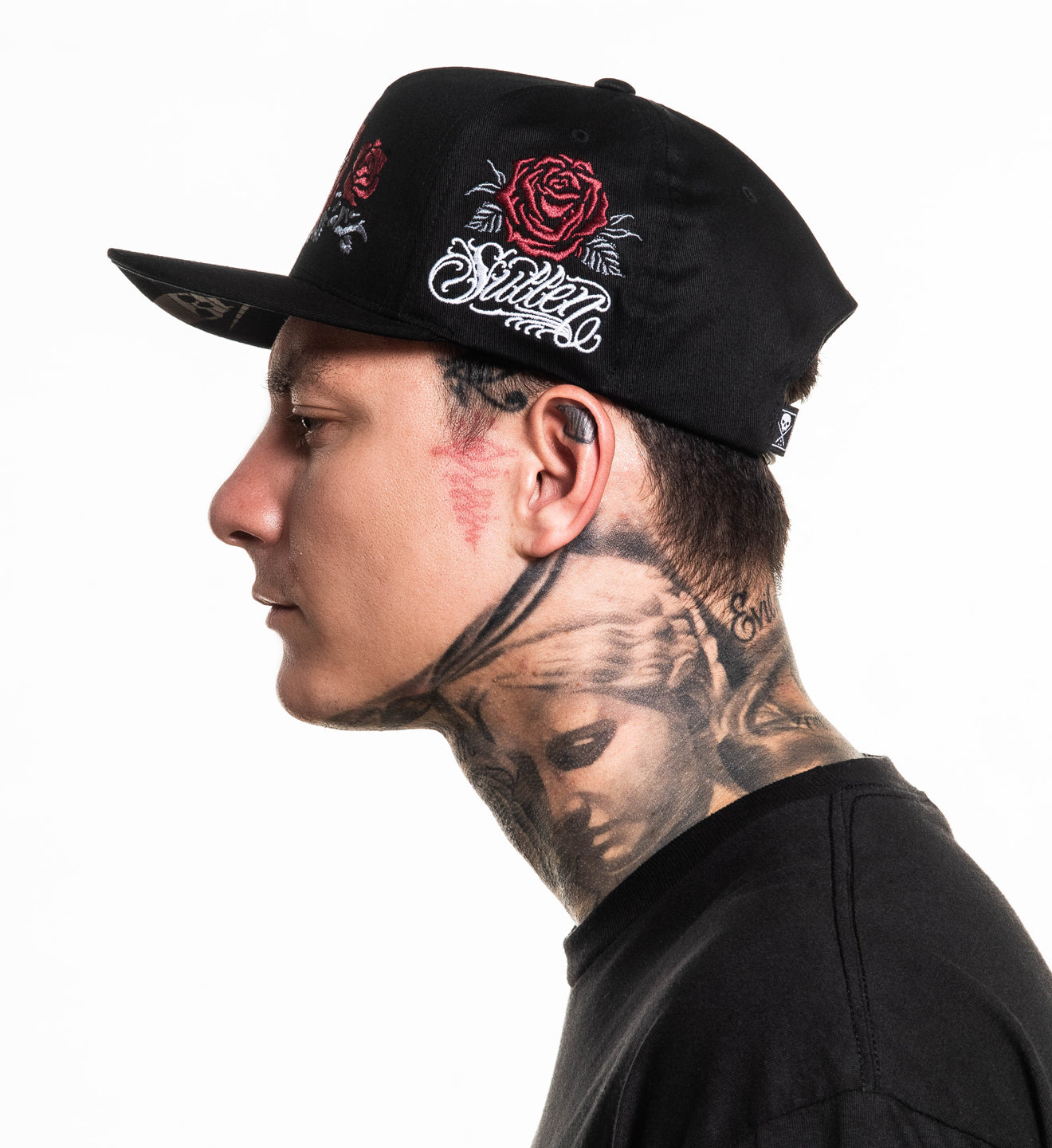 Man wearing a black cap with floral designs and text, against a white background