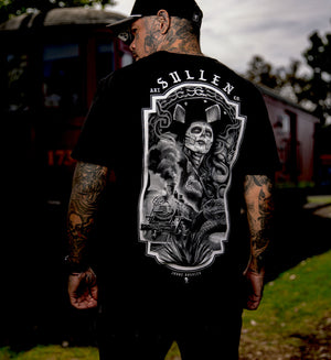 Person wearing a black t-shirt with a detailed graphic design on the back, standing outdoors.
