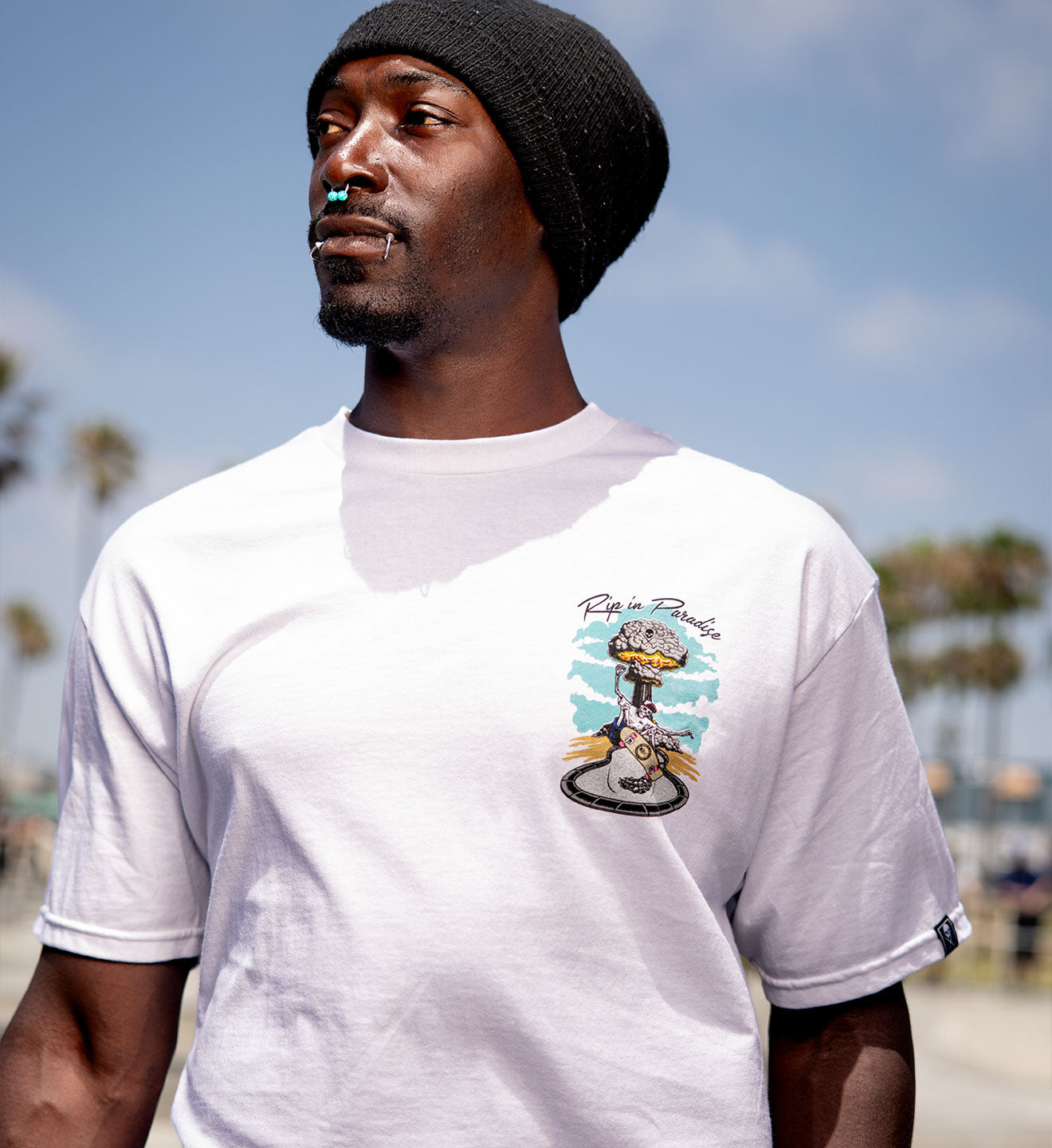Man wearing a white t-shirt with a graphic design on a beach