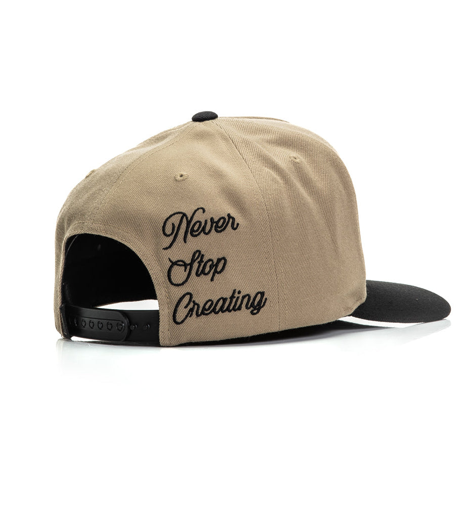Beige cap with 'Never Stop Creating' text on a white background