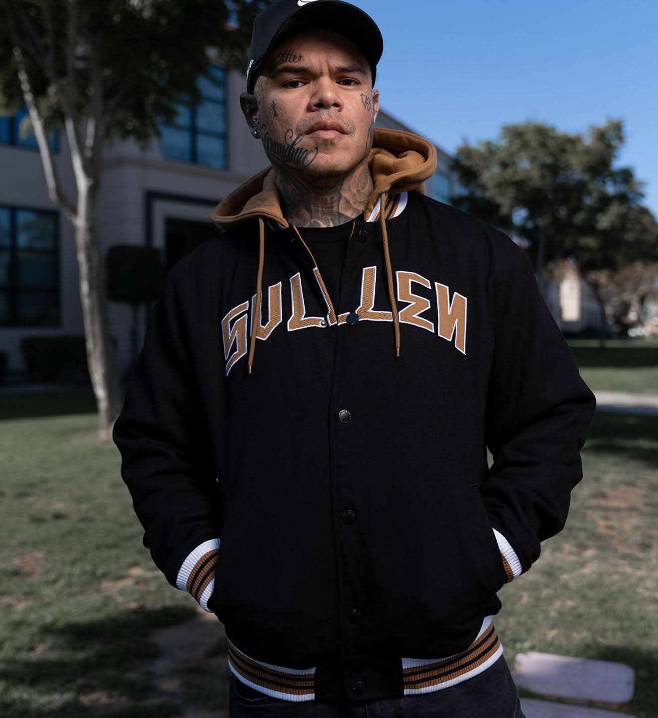 Person wearing a black letterman jacket with 'Gulliver' text, standing outdoors.