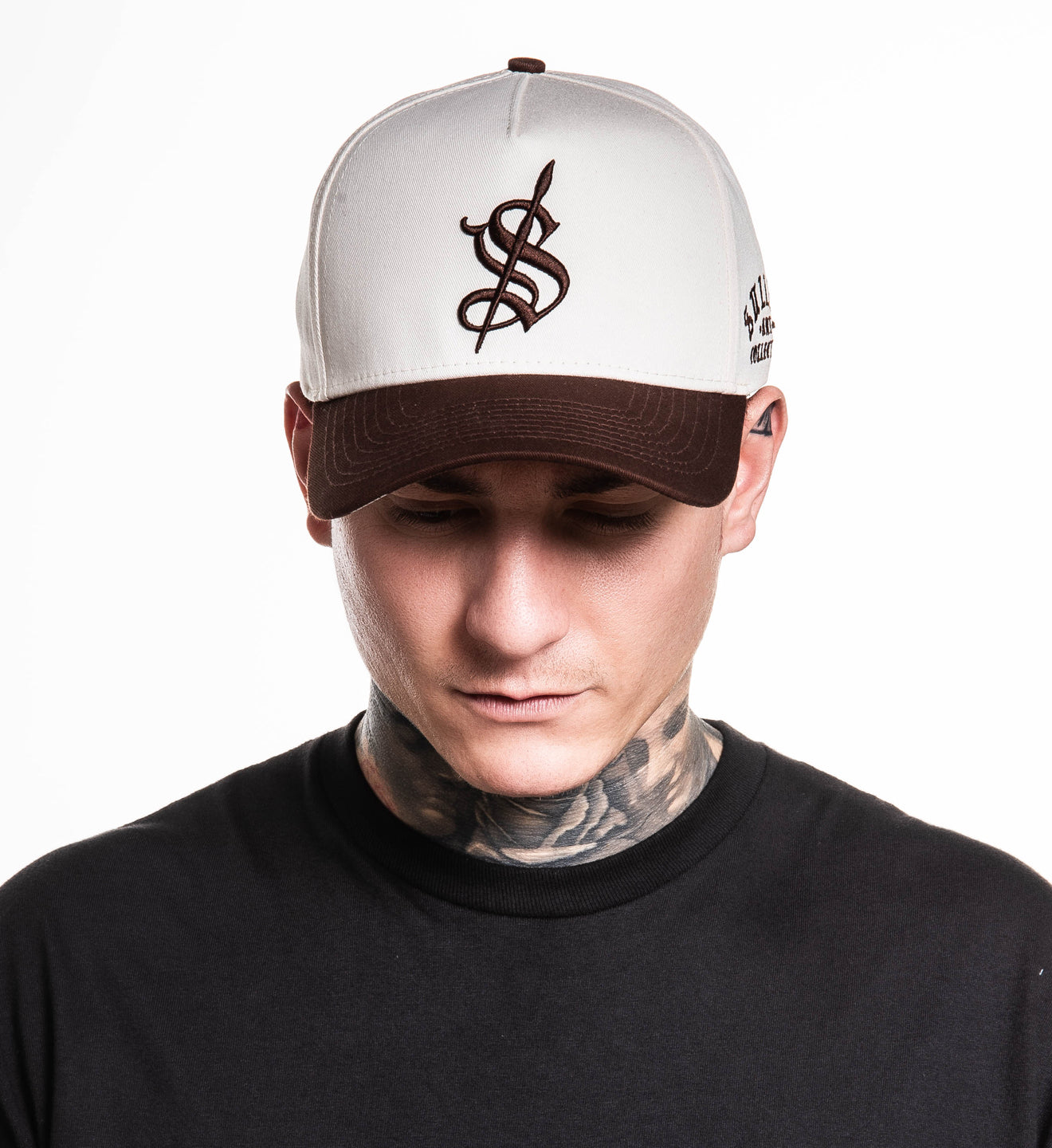 Person wearing a white cap with a brown logo on a white background