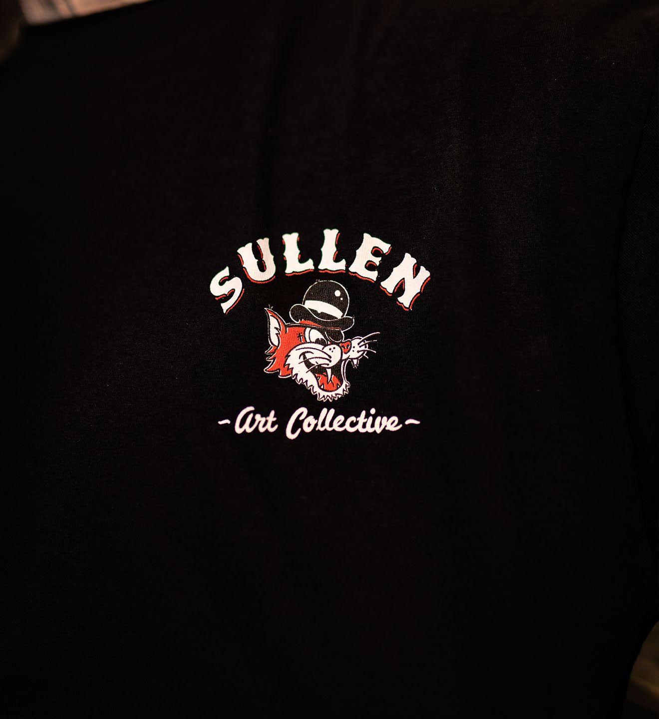 Black t-shirt with Sullen Art Collective logo on a dark background