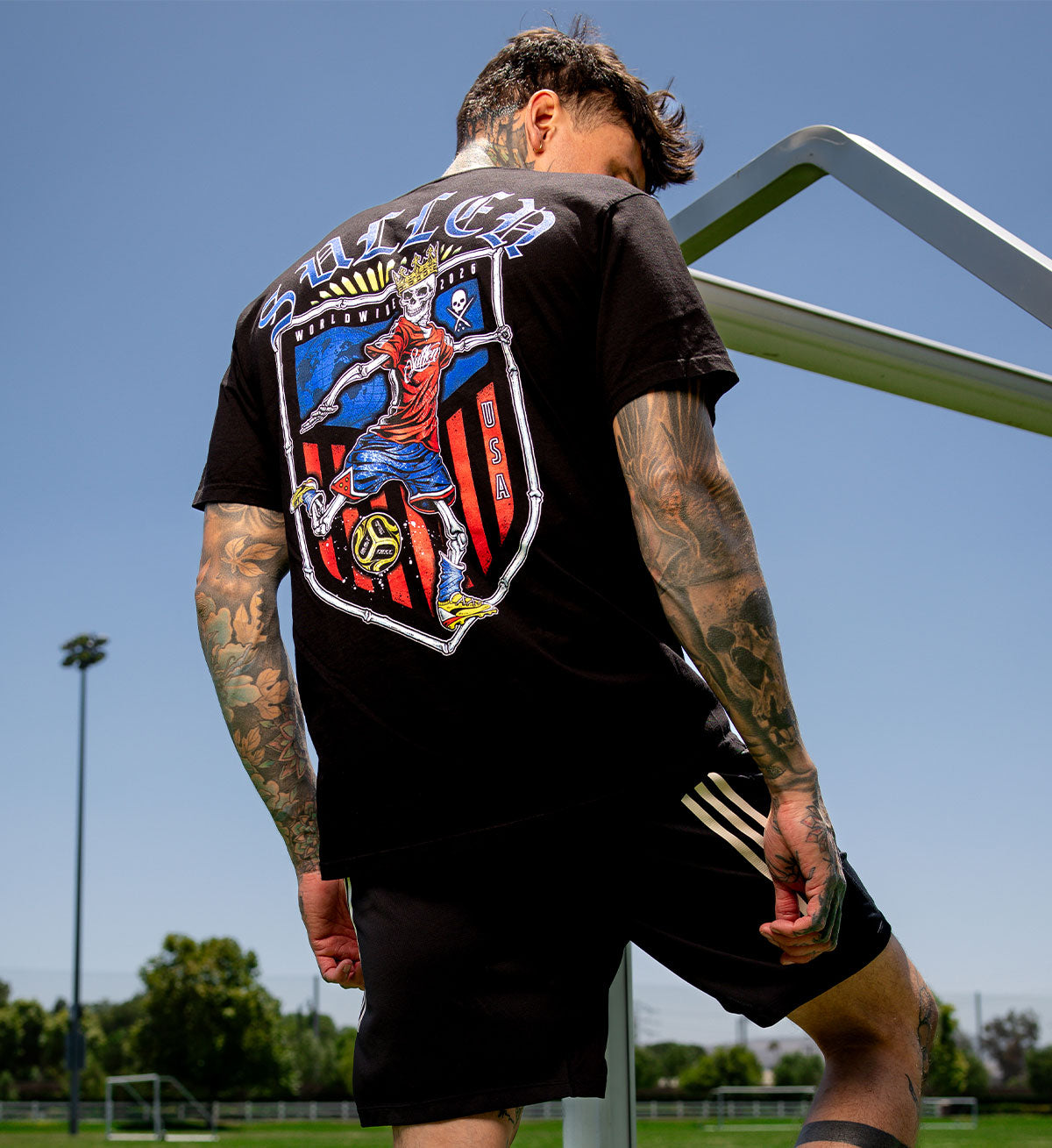 Person wearing a black t-shirt with a colorful graphic on the back, standing outdoors.
