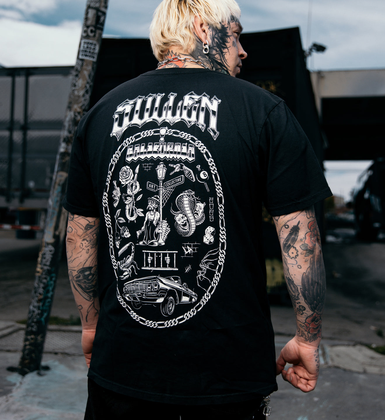 man in a black tee with a white print tattoo graphic on the back