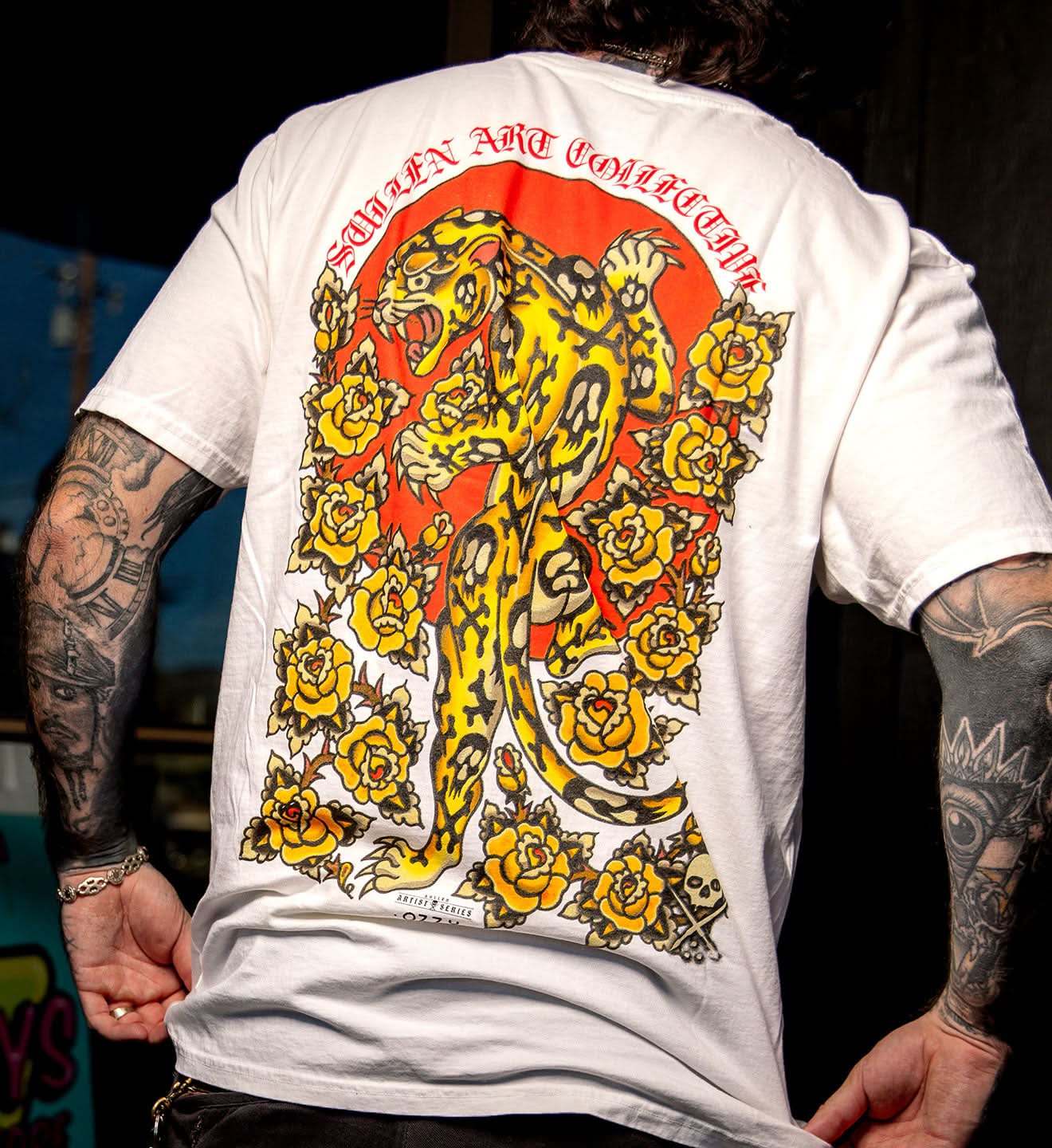 Person wearing a white t-shirt with a colorful tiger design on the back.