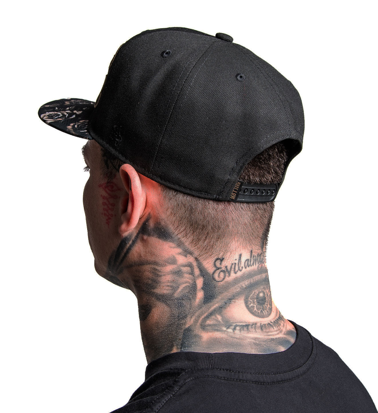 Person wearing a black cap with visible tattoos on the neck and face.