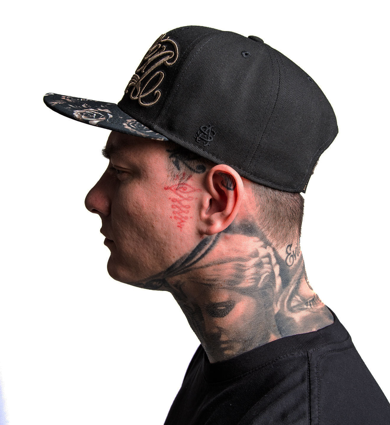 Man wearing a black cap with intricate designs on a white background