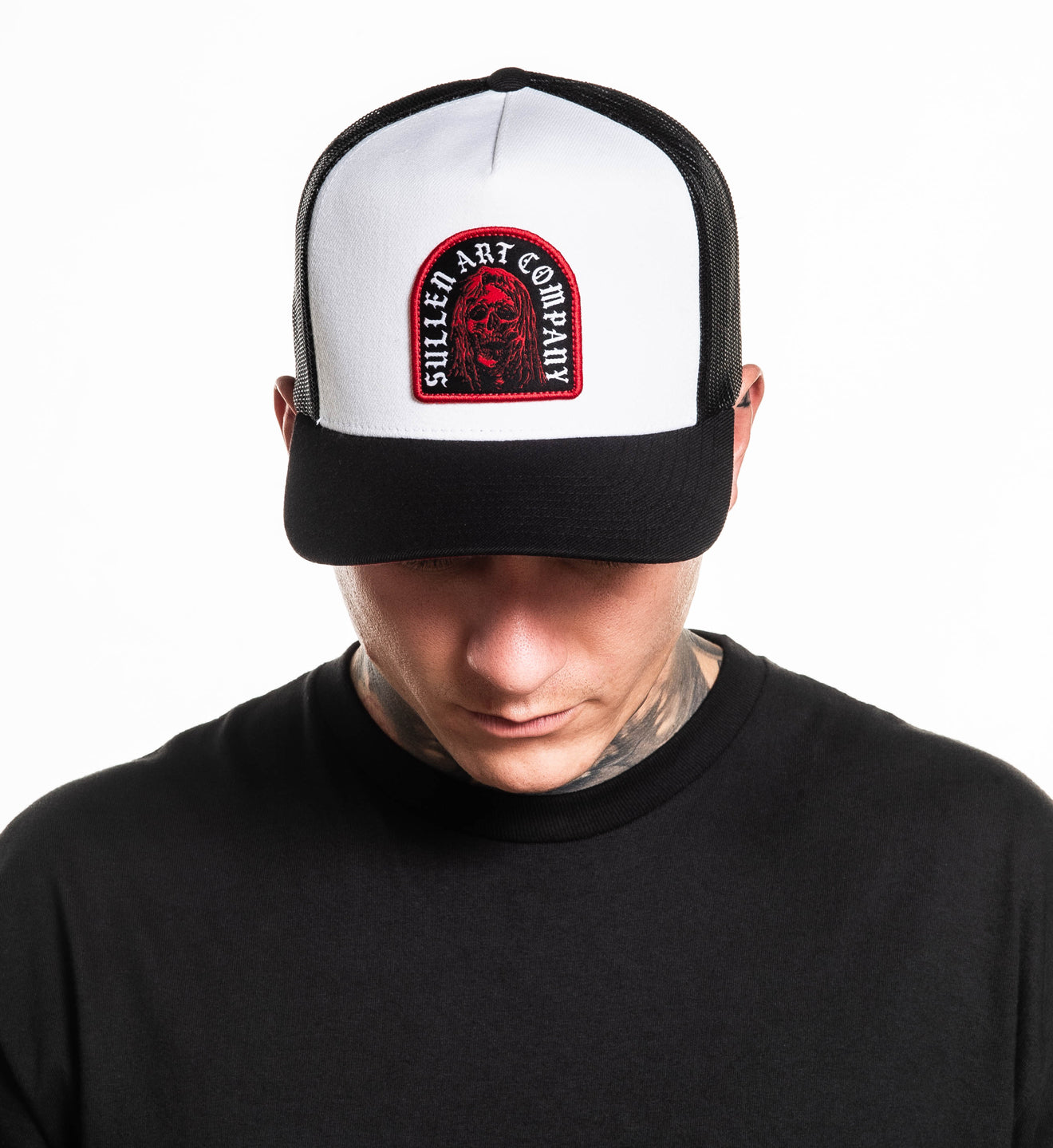 Person wearing a white and black cap with a red and black logo on a white background