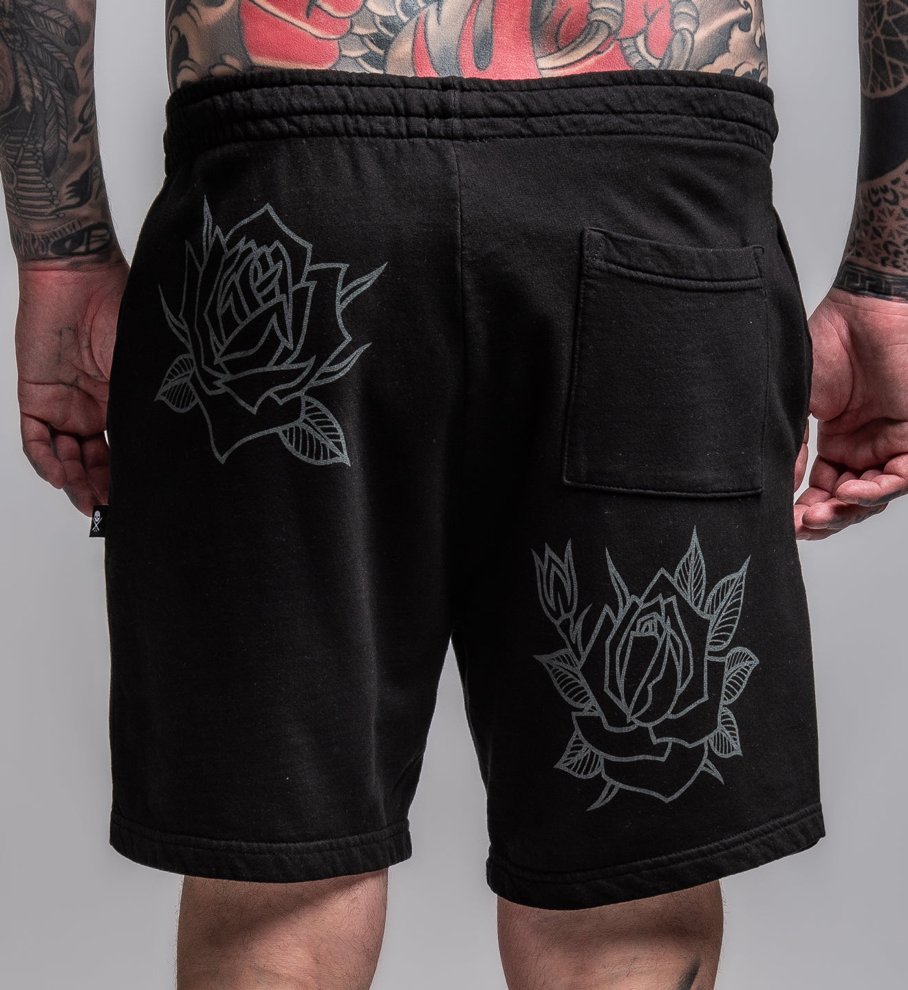 Black shorts with rose designs on a gray background