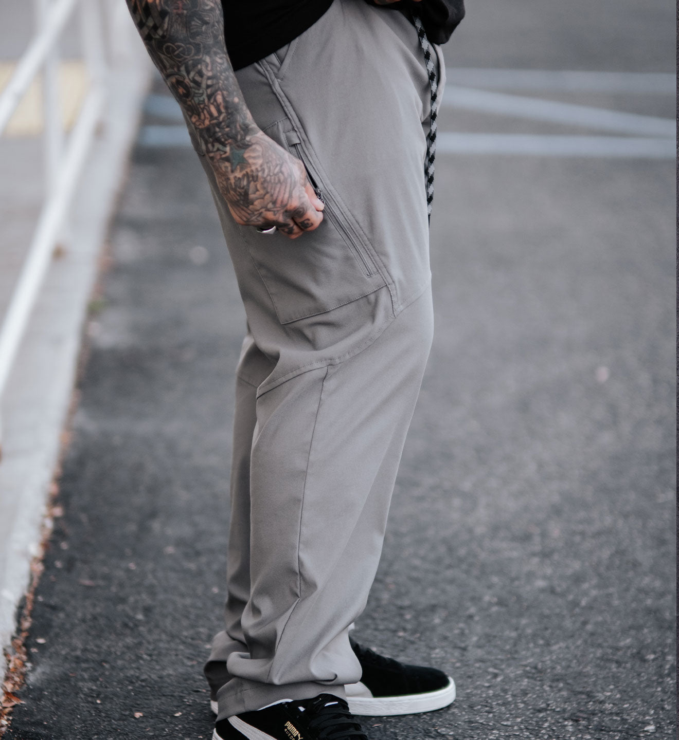 Person wearing gray pants and black sneakers on a street.