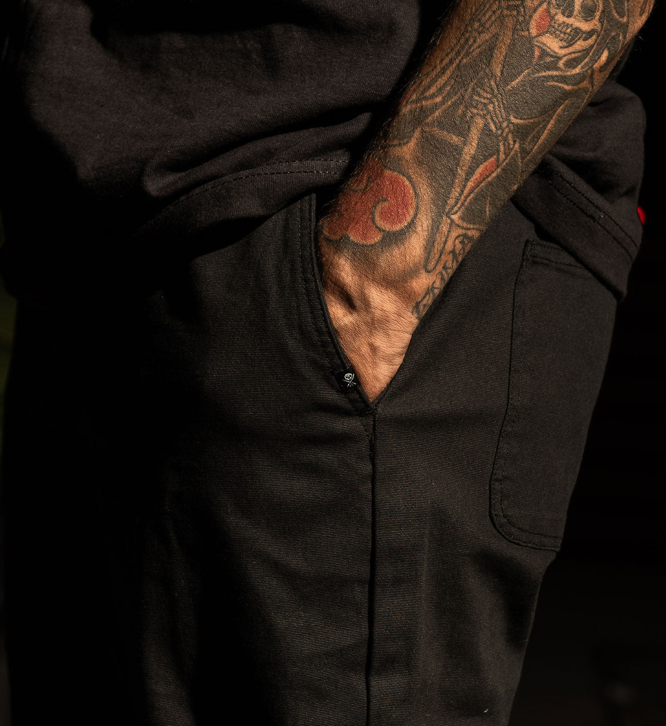 Person wearing a black jacket with a tattooed arm visible