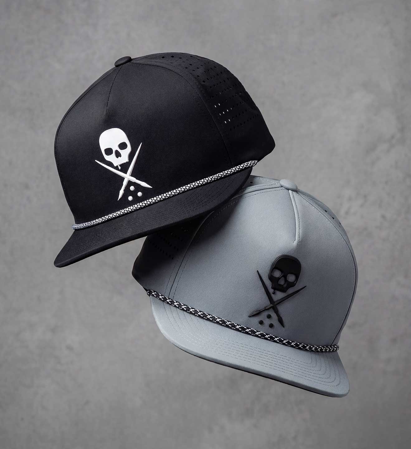 Two caps with skull designs on a gray background