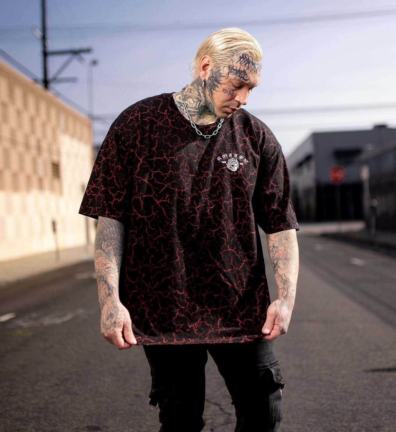 Man wearing a black t-shirt with red patterns on a street.